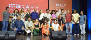 Palestrantes e organizadores em cima do palco do evento, sorrindo.