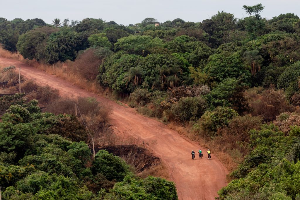 Três pessoas andando de bicicleta em estrada de terra no TransCerrado ocorrido em 2019