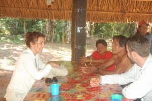Imagem mostra a pesquisadora sentada em uma mesa conversando com três homens. Foto presente no texto O olhar pioneiro de Patrícia Pinho para a ciência da conservação.